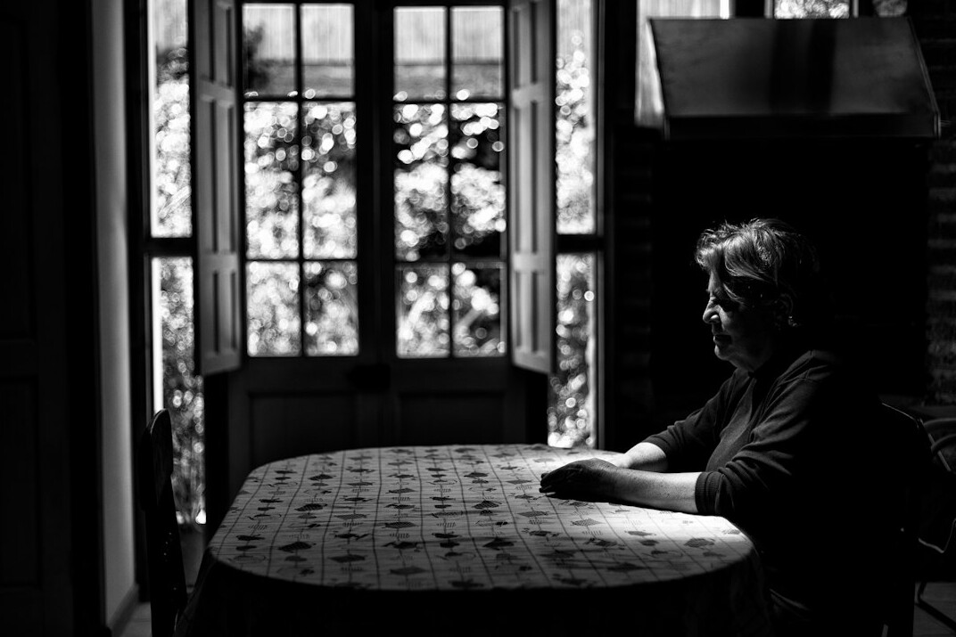 Mature woman counselor talking kindly with an older man across a table